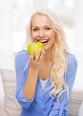Image showing smiling woman with green apple at home