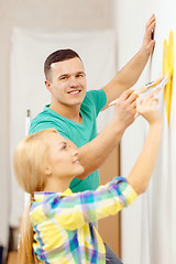 Image showing smiling couple painting small heart on wall