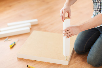 Image showing close up of male hands assemblying legs to table