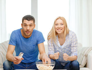 Image showing smiling couple with popcorn cheering sports team