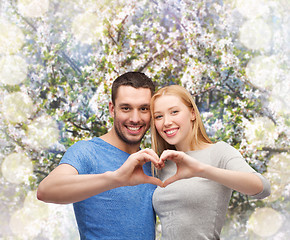 Image showing smiling couple showing heart with hands