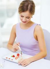 Image showing smiling young woman eating dessert at restaurant