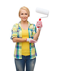 Image showing smiling woman in gloves with paint roller