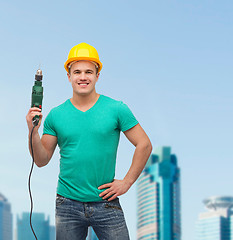 Image showing smiling manual worker in helmet with drill machine