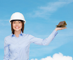Image showing businesswoman in helmet holding house on palm