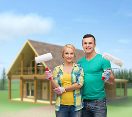 Image showing smiling couple in gloves with paint rollers