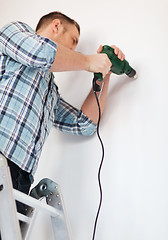 Image showing man with electric drill making hole in wall