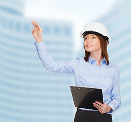 Image showing smiling businesswoman in helmet with clipboard