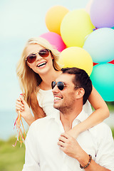 Image showing couple with colorful balloons at seaside