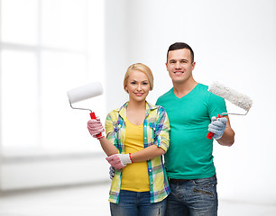 Image showing smiling couple in gloves with paint rollers