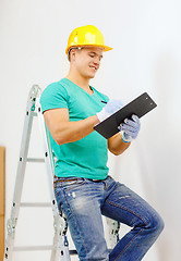 Image showing smiling man in protective helmet with clipboard