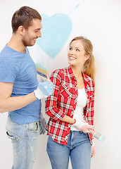 Image showing smiling couple painting small heart on wall