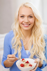 Image showing smiling woman with bowl of muesli having breakfast