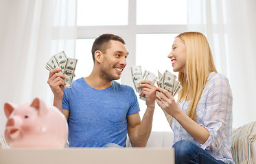 Image showing couple with money and piggybank ot table at home