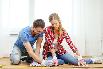 Image showing smiling couple measuring wood flooring