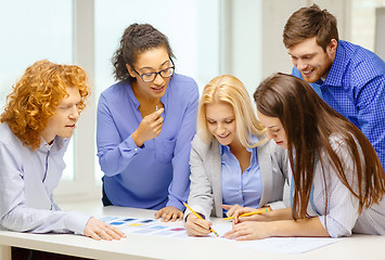 Image showing smiling creative team looking over clothes designs