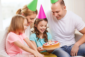Image showing smiling family with two kids in hats with cake