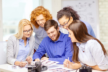 Image showing smiling team with photocamera and images in office