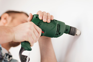 Image showing man with electric drill making hole in wall