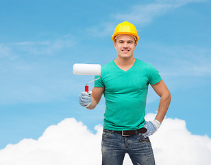 Image showing smiling manual worker in helmet with paint roller