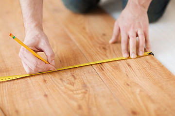 Image showing close up of male hands measuring wood flooring