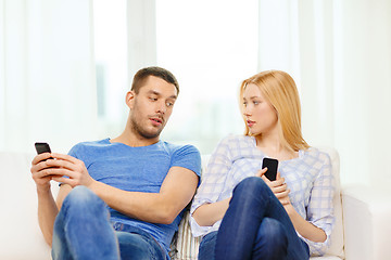 Image showing concentrated couple with smartphones at home