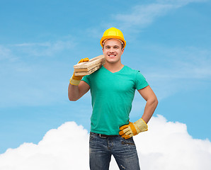 Image showing smiling manual worker in helmet with wooden boards