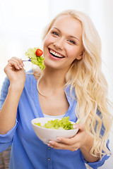 Image showing smiling young woman with green salad at home