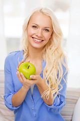Image showing smiling woman with green apple at home