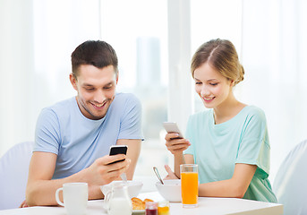 Image showing smiling couple with smartphones reading news