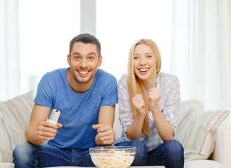 Image showing smiling couple with popcorn cheering sports team