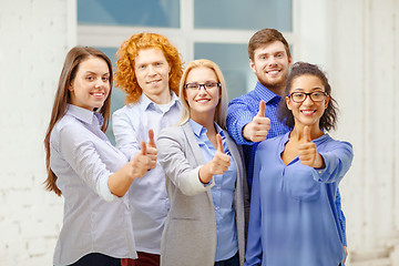 Image showing happy creative team showing thumbs up in office