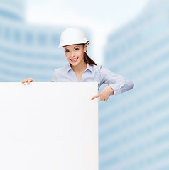 Image showing businesswoman in helmet pointing finger to board