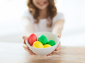 Image showing close up of girl holding bowl with colored eggs