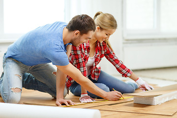 Image showing smiling couple measuring wood flooring