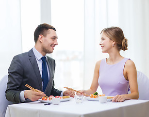 Image showing smiling couple eating sushi at restaurant