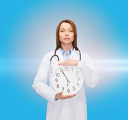 Image showing calm female doctor with wall clock