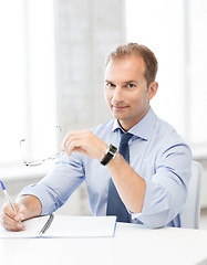 Image showing businessman with spectacles writing in notebook