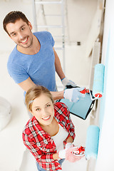 Image showing smiling couple painting wall at home