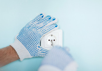 Image showing close up of male in gloves installing new socket