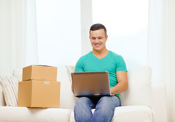 Image showing man with laptop and cardboard boxes at home