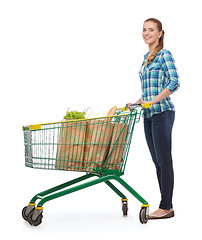 Image showing smiling young woman with shopping cart and food