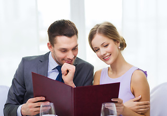 Image showing smiling couple with menu at restaurant