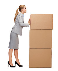 Image showing smiling businesswoman pushing tower of cardboards