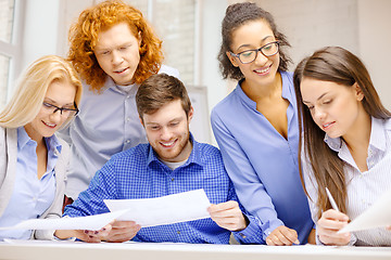 Image showing smiling team with paper at office