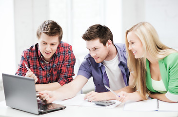 Image showing smiling students looking at laptop at school