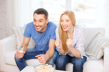 Image showing smiling couple with popcorn cheering sports team