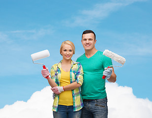 Image showing smiling couple in gloves with paint rollers