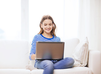 Image showing smiling teenage girl with laptop computer at home