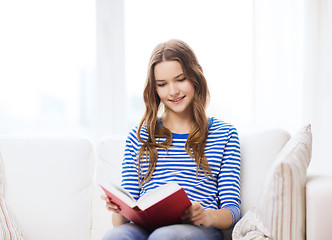 Image showing smiling teenage girl reading book on couch